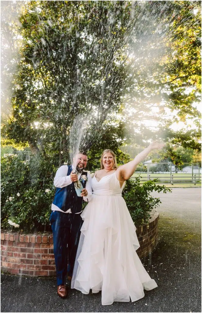 Snohomish Wedding Photographer GSquared Weddings A bride and groom celebrate by popping a champagne bottle with the cork flying and champagne spraying They stand in front of a lush tree with sunlight filtering through the leaves The bride smiles and raises her arm joyfully Serving Seattle Snohomish and Washington State Snohomish Wedding Photographer GSquared Weddings A bride and groom celebrate by popping a champagne bottle, with the cork flying and champagne spraying. They stand in front of a lush tree, with sunlight filtering through the leaves. The bride smiles and raises her arm joyfully. Serving Seattle, Snohomish and Washington State