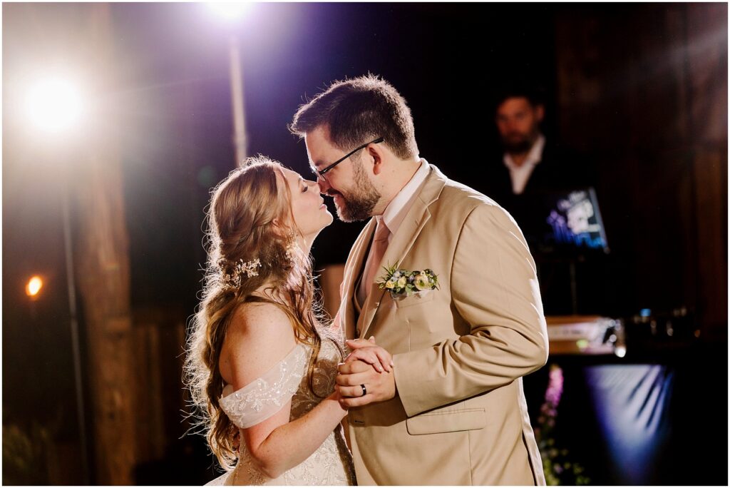 Snohomish wedding photographer gsquared weddings a couple shares a romantic dance at a wedding The woman in a white gown with floral details and the man in a beige suit with a boutonnière gently lean in close to each other Soft lighting highlights their expressions Serving seattle snohomish and washington state