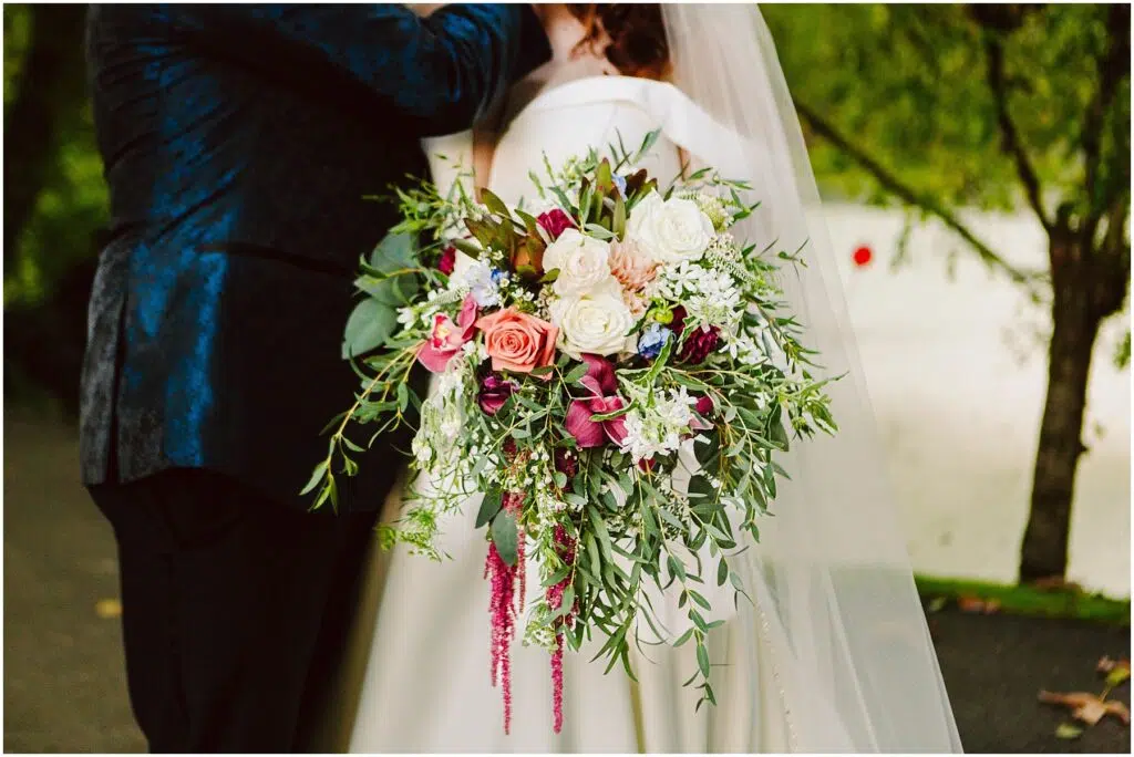 Snohomish Wedding Photographer GSquared Weddings Bride holding a large vibrant bouquet of pink white and purple flowers with green foliage She stands beside a person in a dark suit Background shows trees and a white surface possibly a building or wall Serving Seattle Snohomish and Washington State Snohomish Wedding Photographer GSquared Weddings Bride holding a large, vibrant bouquet of pink, white, and purple flowers with green foliage. She stands beside a person in a dark suit. Background shows trees and a white surface, possibly a building or wall. Serving Seattle, Snohomish and Washington State