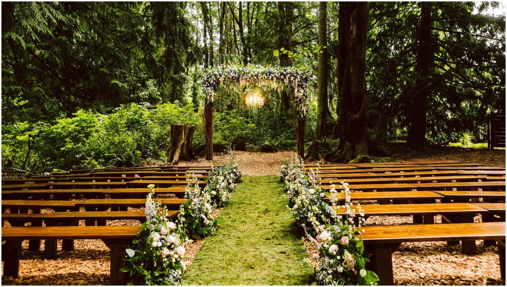 Snohomish wedding photographer gsquared weddings a serene outdoor wedding setup in a forest Wooden benches line a grassy aisle adorned with floral arrangements An arch decorated with flowers stands at the end surrounded by lush green trees and soft sunlight filtering through the leaves Serving seattle snohomish and washington state Snohomish wedding photographer gsquared weddings a serene outdoor wedding setup in a forest Wooden benches line a grassy aisle adorned with floral arrangements An arch decorated with flowers stands at the end surrounded by lush green trees and soft sunlight filtering through the leaves Serving seattle snohomish and washington state