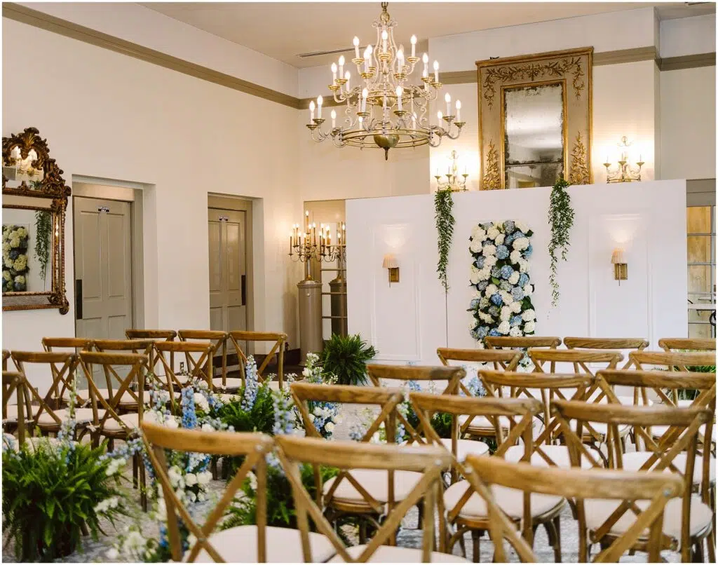 Snohomish Wedding Photographer GSquared Weddings Elegant wedding ceremony room with wooden chairs facing a white wall adorned with floral arrangements Chandeliers and mirrors add sophistication while greenery accents the space Neutral tones create a serene atmosphere Serving Seattle Snohomish and Washington State Snohomish Wedding Photographer GSquared Weddings Elegant wedding ceremony room with wooden chairs facing a white wall adorned with floral arrangements. Chandeliers and mirrors add sophistication, while greenery accents the space. Neutral tones create a serene atmosphere. Serving Seattle, Snohomish and Washington State