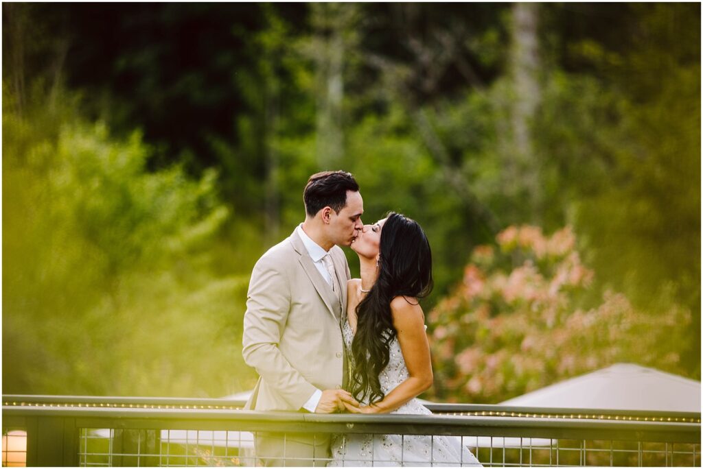 Snohomish wedding photographer gsquared weddings a couple kisses on a bridge in a lush green park The man in a beige suit and the woman in a white dress share an intimate moment surrounded by greenery and blurred floral backgrounds Serving seattle snohomish and washington state Snohomish wedding photographer gsquared weddings a couple kisses on a bridge in a lush green park The man in a beige suit and the woman in a white dress share an intimate moment surrounded by greenery and blurred floral backgrounds Serving seattle snohomish and washington state