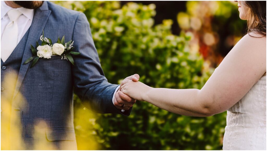 Snohomish wedding photographer gsquared weddings a couple holding hands dressed formally The person on the left wears a blue suit with a white boutonniere The person on the right is in a white dress The background is filled with greenery Serving seattle snohomish and washington state Snohomish wedding photographer gsquared weddings a couple holding hands dressed formally The person on the left wears a blue suit with a white boutonniere The person on the right is in a white dress The background is filled with greenery Serving seattle snohomish and washington state