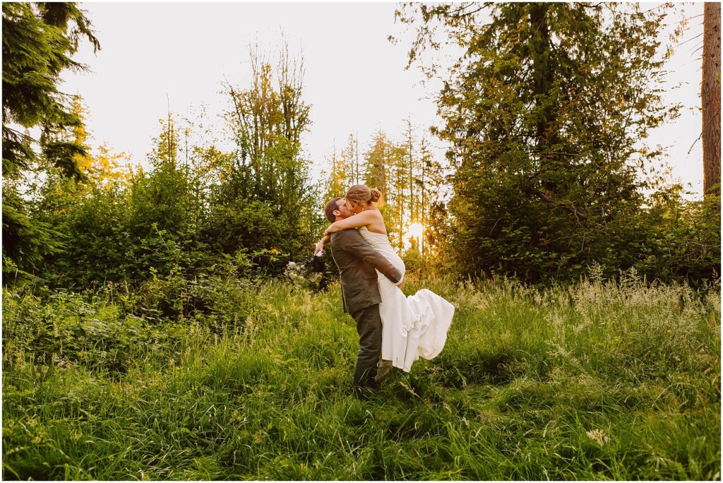 Snohomish wedding photographer gsquared weddings a couple in wedding attire embrace joyfully in a lush green forest clearing The sun sets in the background casting a warm glow over the scene The bride is lifted off the ground by the groom surrounded by tall trees and grass Serving seattle snohomish and washington state Snohomish wedding photographer gsquared weddings a couple in wedding attire embrace joyfully in a lush green forest clearing The sun sets in the background casting a warm glow over the scene The bride is lifted off the ground by the groom surrounded by tall trees and grass Serving seattle snohomish and washington state
