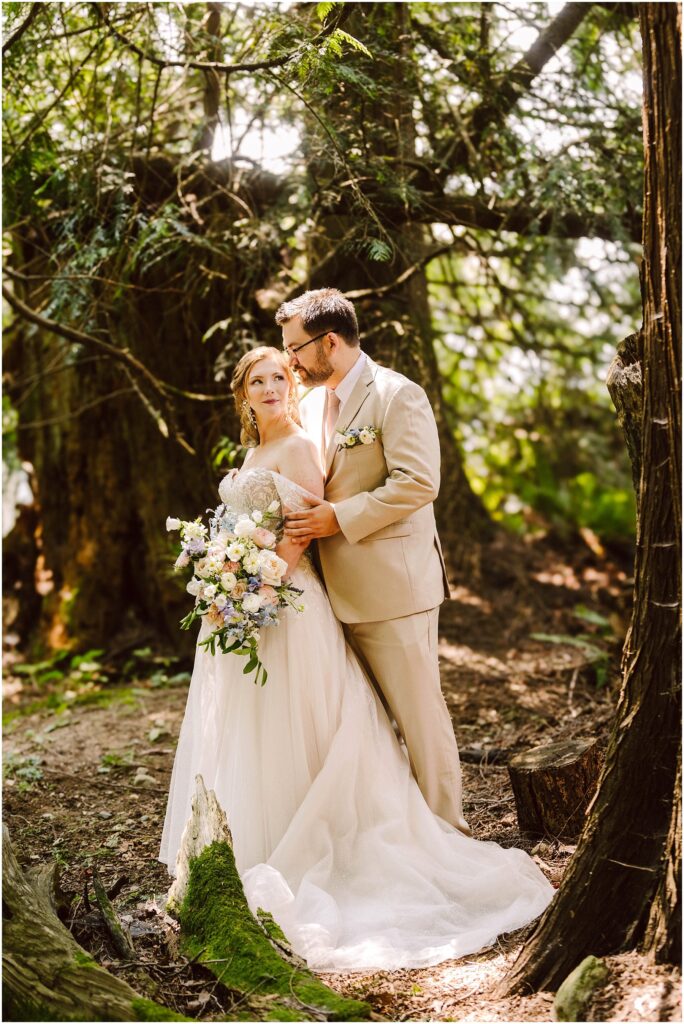 Snohomish wedding photographer gsquared weddings bride and groom stand together in a wooded area The bride holding a bouquet of flowers wears a white gown while the groom is in a light tan suit Sunlight filters through the trees creating a serene and romantic atmosphere Serving seattle snohomish and washington state Snohomish wedding photographer gsquared weddings bride and groom stand together in a wooded area The bride holding a bouquet of flowers wears a white gown while the groom is in a light tan suit Sunlight filters through the trees creating a serene and romantic atmosphere Serving seattle snohomish and washington state