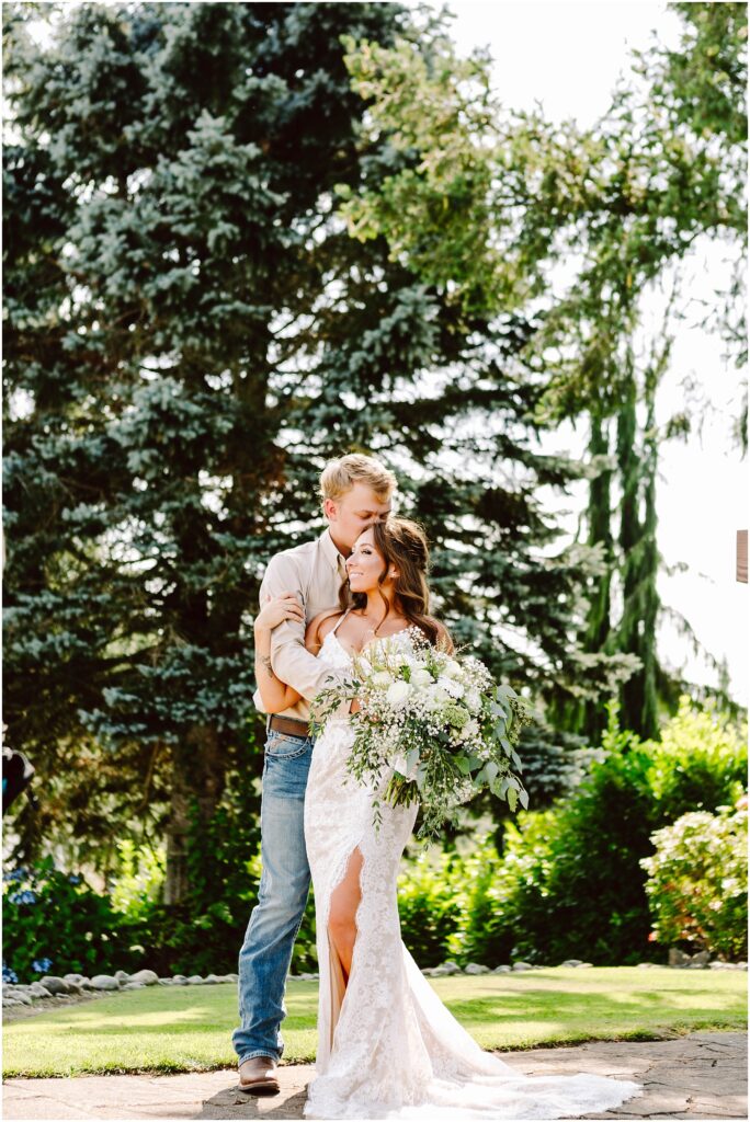 Snohomish wedding photographer gsquared weddings a couple embraces outdoors in front of lush greenery and large trees The woman in a white lace wedding dress holding a bouquet stands closely with a man in a beige shirt and jeans Sunlight filters through the foliage creating a serene ambiance Serving seattle snohomish and washington state Snohomish wedding photographer gsquared weddings a couple embraces outdoors in front of lush greenery and large trees The woman in a white lace wedding dress holding a bouquet stands closely with a man in a beige shirt and jeans Sunlight filters through the foliage creating a serene ambiance Serving seattle snohomish and washington state