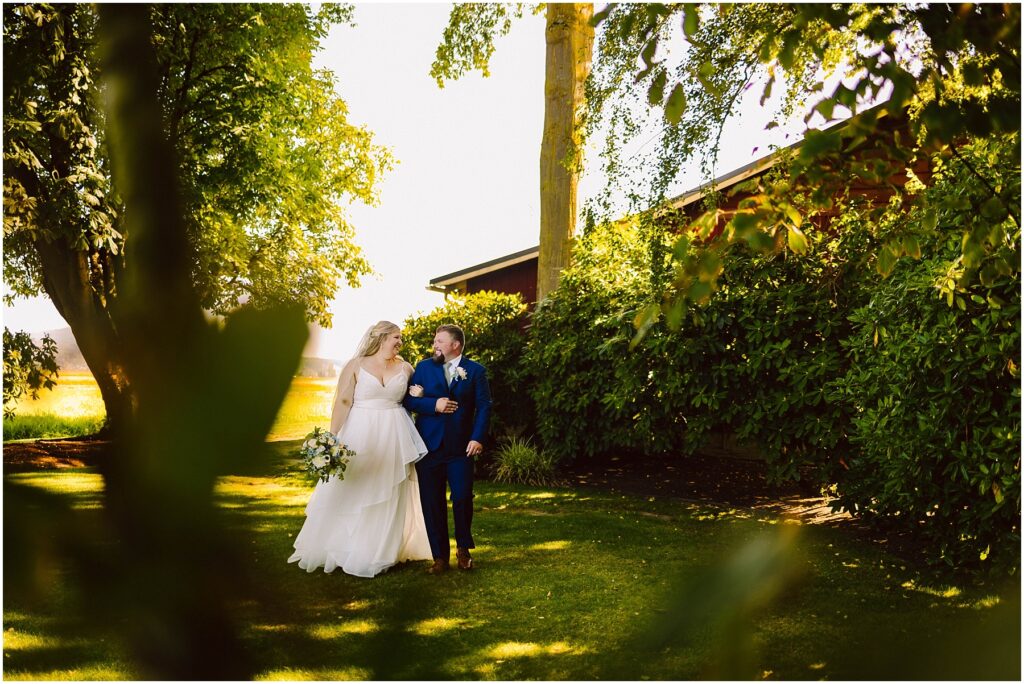 Snohomish wedding photographer gsquared weddings a bride and groom walk hand in hand through a sunlit garden surrounded by lush green trees and bushes The bride wears a white dress and the groom is in a dark suit Sunlight filters through the leaves casting gentle shadows Serving seattle snohomish and washington state Snohomish wedding photographer gsquared weddings a bride and groom walk hand in hand through a sunlit garden surrounded by lush green trees and bushes The bride wears a white dress and the groom is in a dark suit Sunlight filters through the leaves casting gentle shadows Serving seattle snohomish and washington state