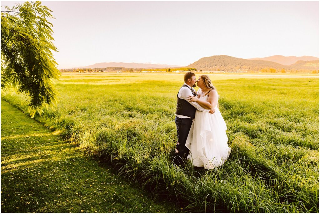 Snohomish wedding photographer gsquared weddings a bride and groom stand embracing in a green field under a clear sky The bride wears a white dress and the groom is in a vest and tie A tree and distant mountains frame the idyllic scene Serving seattle snohomish and washington state Snohomish wedding photographer gsquared weddings a bride and groom stand embracing in a green field under a clear sky The bride wears a white dress and the groom is in a vest and tie A tree and distant mountains frame the idyllic scene Serving seattle snohomish and washington state