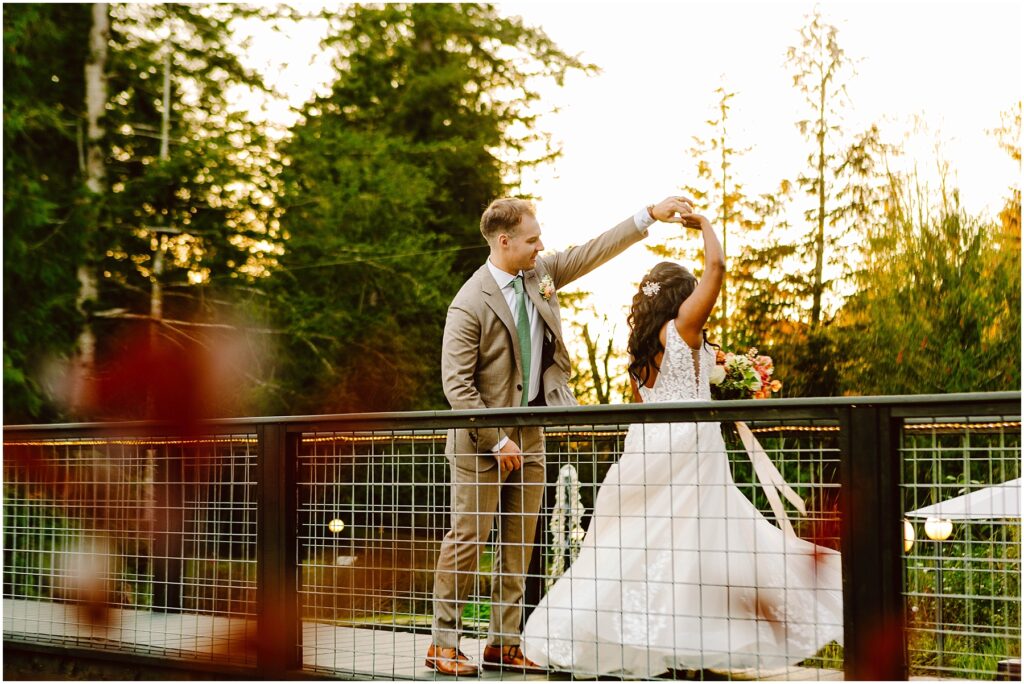 Snohomish wedding photographer gsquared weddings a groom in a brown suit twirls his bride who is wearing a white wedding dress on a wooden bridge They are surrounded by trees with a warm sunset glow in the background Serving seattle snohomish and washington state Snohomish wedding photographer gsquared weddings a groom in a brown suit twirls his bride who is wearing a white wedding dress on a wooden bridge They are surrounded by trees with a warm sunset glow in the background Serving seattle snohomish and washington state