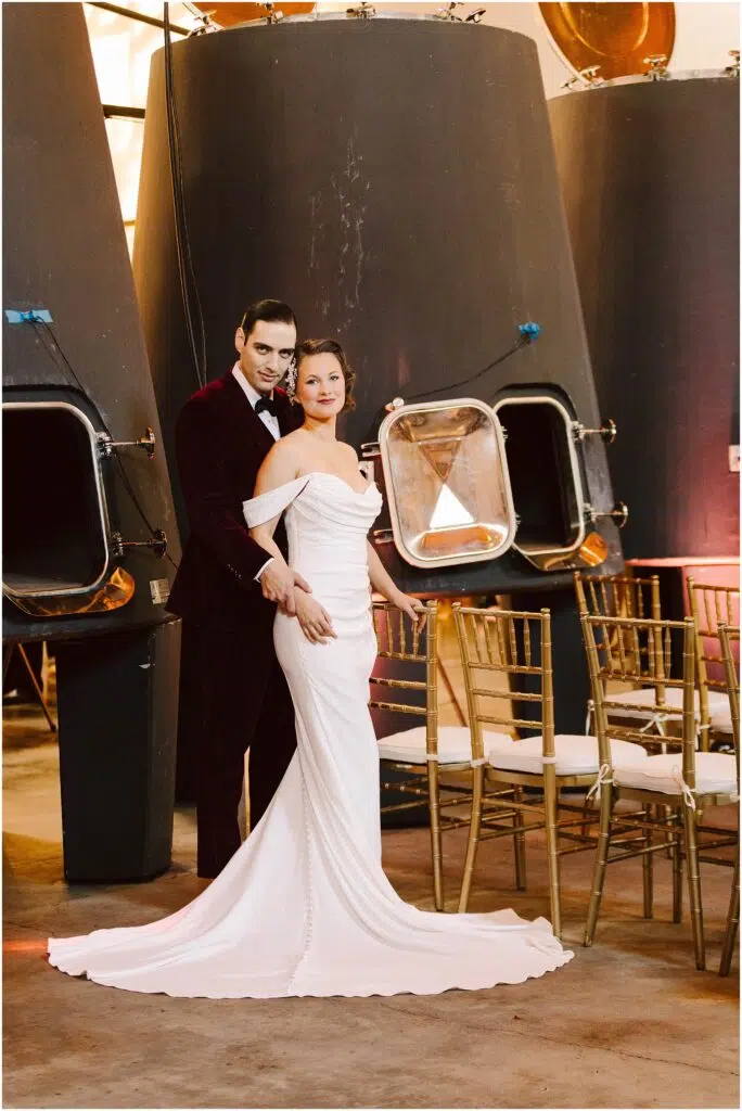 Snohomish Wedding Photographer GSquared Weddings A couple stands in front of large industrial tanks The woman wears an offshoulder white gown and the man wears a burgundy suit They are surrounded by rows of chairs suggesting a wedding or formal event setting Serving Seattle Snohomish and Washington State Snohomish Wedding Photographer GSquared Weddings A couple stands in front of large industrial tanks. The woman wears an off-shoulder white gown, and the man wears a burgundy suit. They are surrounded by rows of chairs, suggesting a wedding or formal event setting. Serving Seattle, Snohomish and Washington State