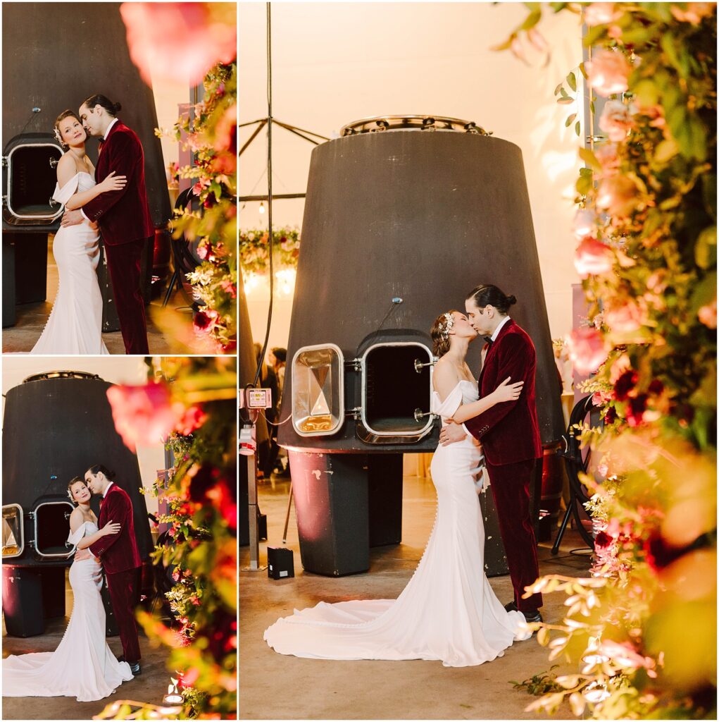 Snohomish Wedding Photographer GSquared Weddings A couple, dressed in wedding attire, embraces and kisses in front of a large industrial structure. Theyre surrounded by vibrant floral arrangements. The bride wears a white gown, and the groom is in a red suit. The scene has a warm, romantic ambiance. Serving Seattle, Snohomish and Washington State