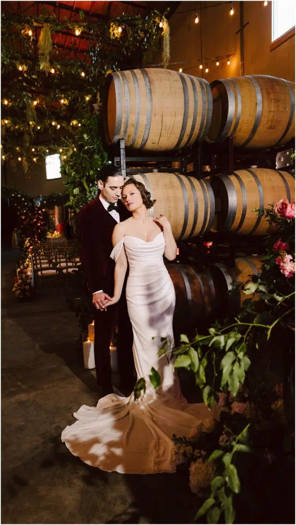 Snohomish Wedding Photographer GSquared Weddings A couple stands in a romantic winery setting The woman is in a white gown and the man is in a dark suit They hold hands near a stack of wooden barrels surrounded by warm lighting and lush greenery Serving Seattle Snohomish and Washington State Snohomish Wedding Photographer GSquared Weddings A couple stands in a romantic winery setting. The woman is in a white gown, and the man is in a dark suit. They hold hands near a stack of wooden barrels, surrounded by warm lighting and lush greenery. Serving Seattle, Snohomish and Washington State