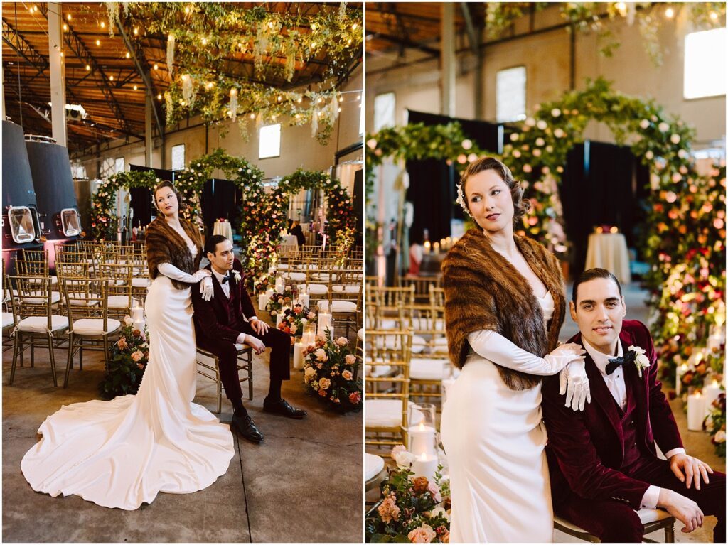 Snohomish Wedding Photographer GSquared Weddings A bride in a white gown and fur stole stands beside a seated groom in a burgundy suit. They are in a decorated indoor venue with flower arrangements and chandelier lights. The setting appears elegant and romantic. Serving Seattle, Snohomish and Washington State