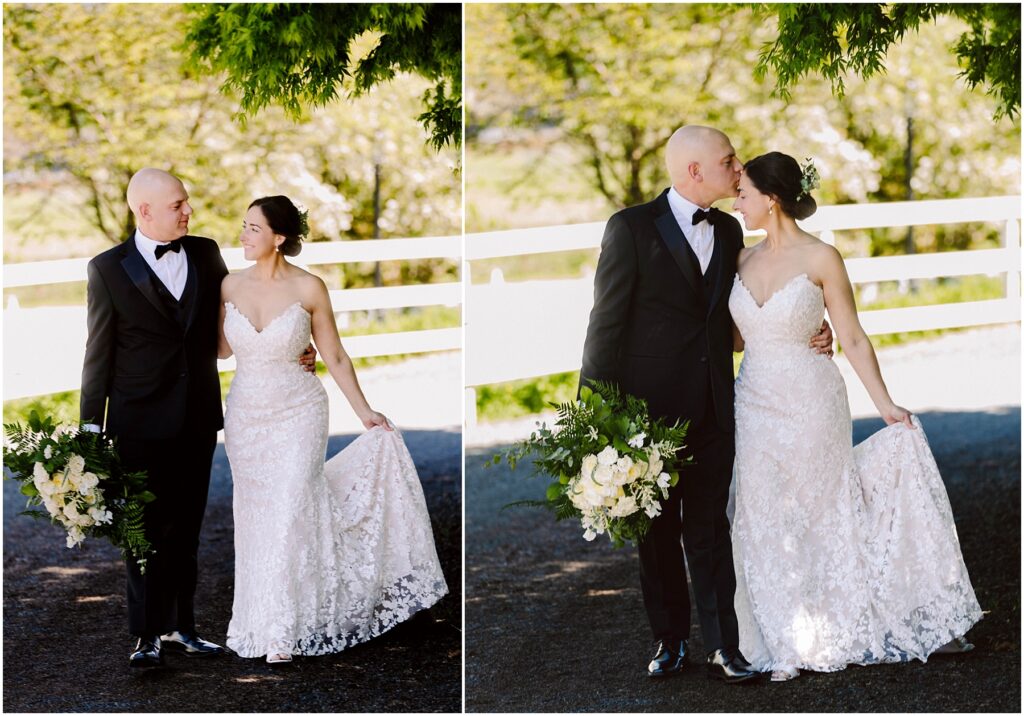 Snohomish Wedding Photographer GSquared Weddings A bride and groom walk arm in arm on a sunlit path against a white fence. The bride wears a lacy white gown and holds a bouquet of white flowers. The groom is in a black suit. They share joyful expressions and a kiss. Trees provide a lush background. Serving Seattle, Snohomish and Washington State