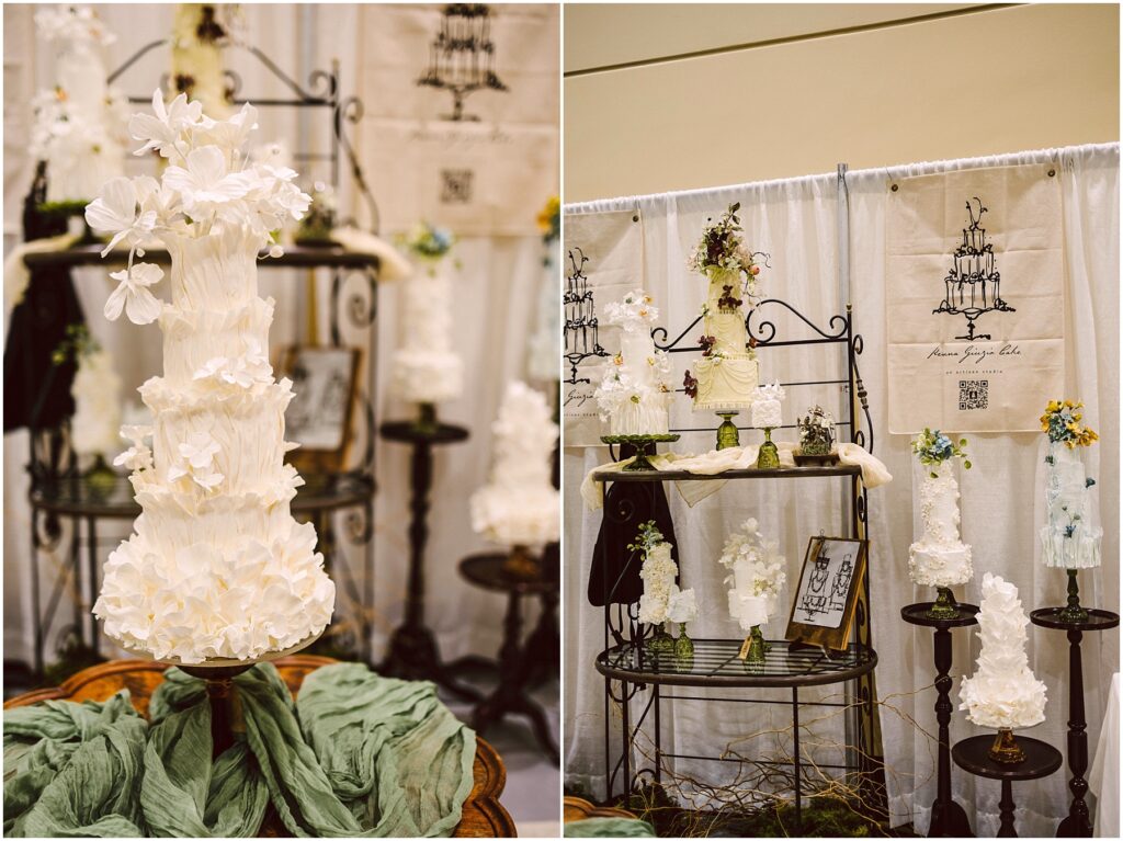 Snohomish Wedding Photographer GSquared Weddings Tall, intricately designed white wedding cakes adorned with delicate floral decorations are displayed on elegant metal stands. The setup includes green fabric accents and framed artwork against a backdrop featuring cake illustrations. Serving Seattle, Snohomish and Washington State
