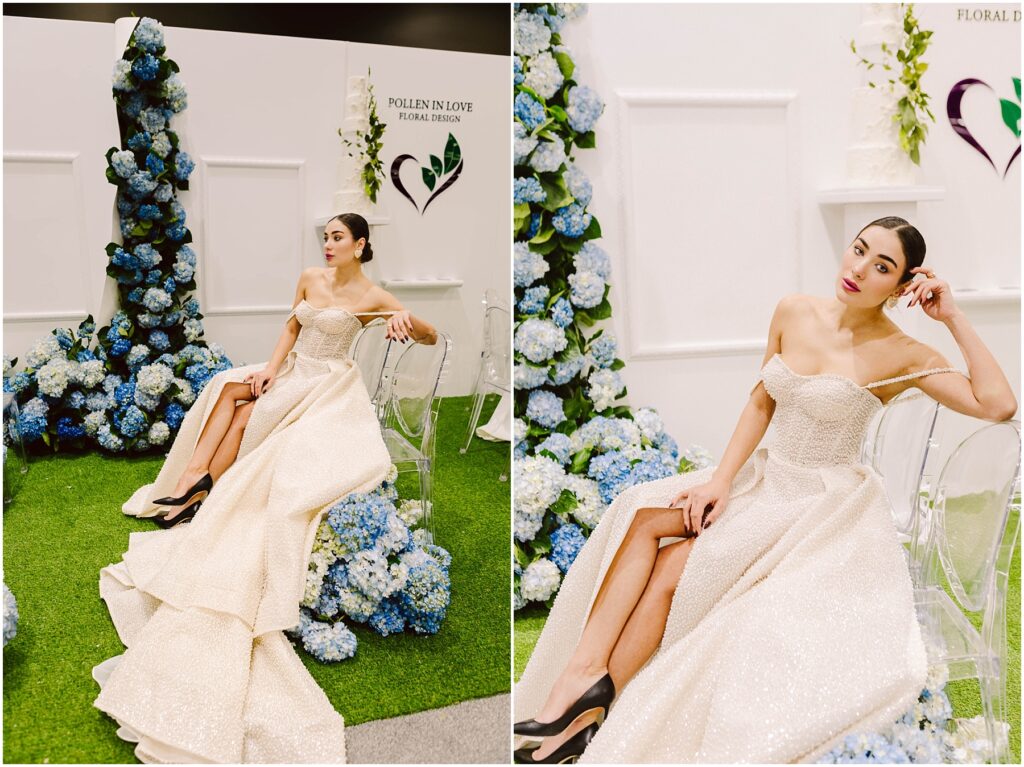 Snohomish Wedding Photographer GSquared Weddings A woman in an elegant, off-shoulder gown sits on a clear chair surrounded by blue hydrangeas. The setting includes green artificial grass and a white backdrop with Pollen in Love Floral Design displayed. Serving Seattle, Snohomish and Washington State