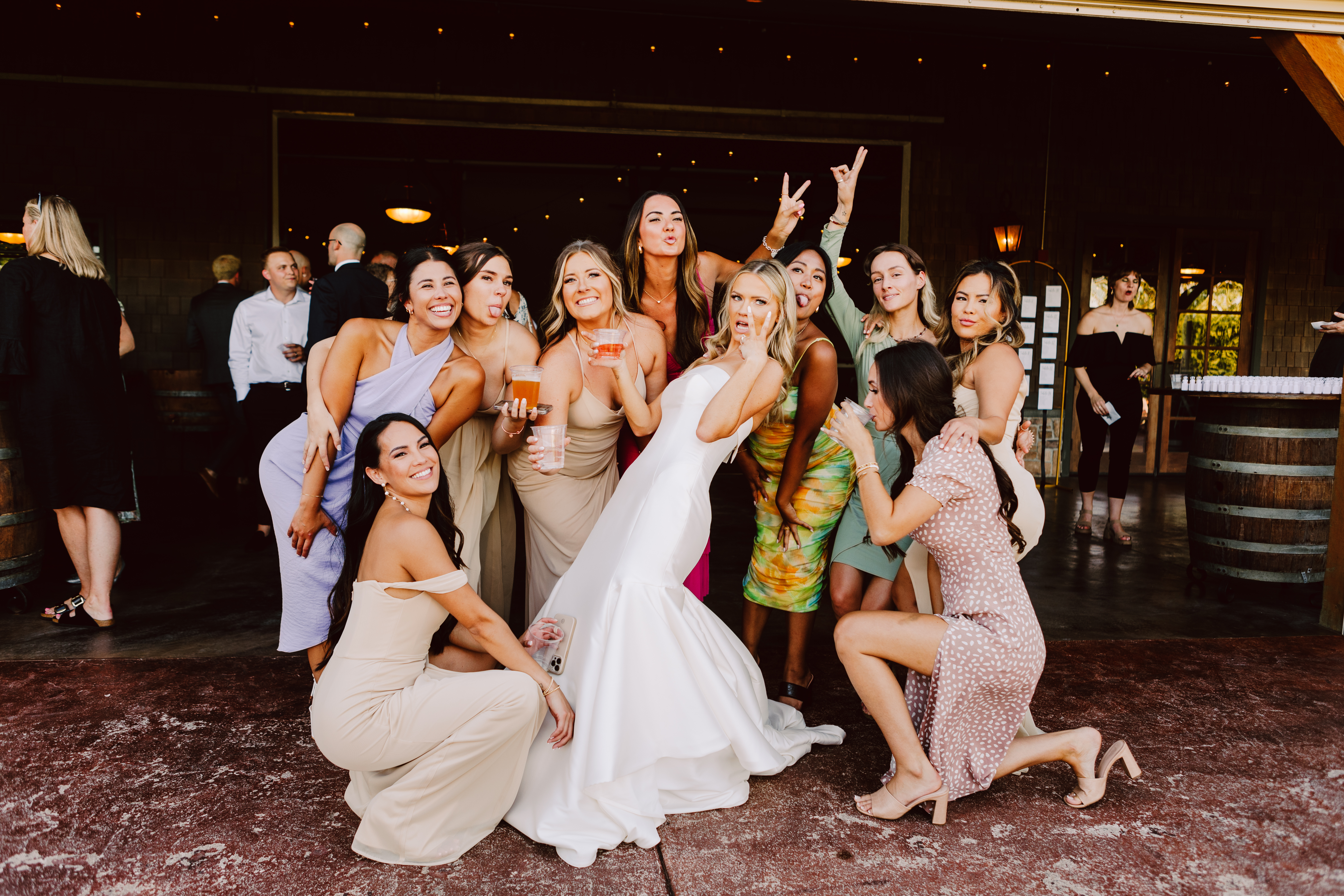 Snohomish Wedding Photographer GSquared Weddings A group of women including a bride in a white dress pose happily with a guest on the patio They are dressed in colorful dresses and making cheerful expressions and gestures The setting exudes the joyous spirit of a celebration or wedding Serving Seattle Snohomish and Washington State