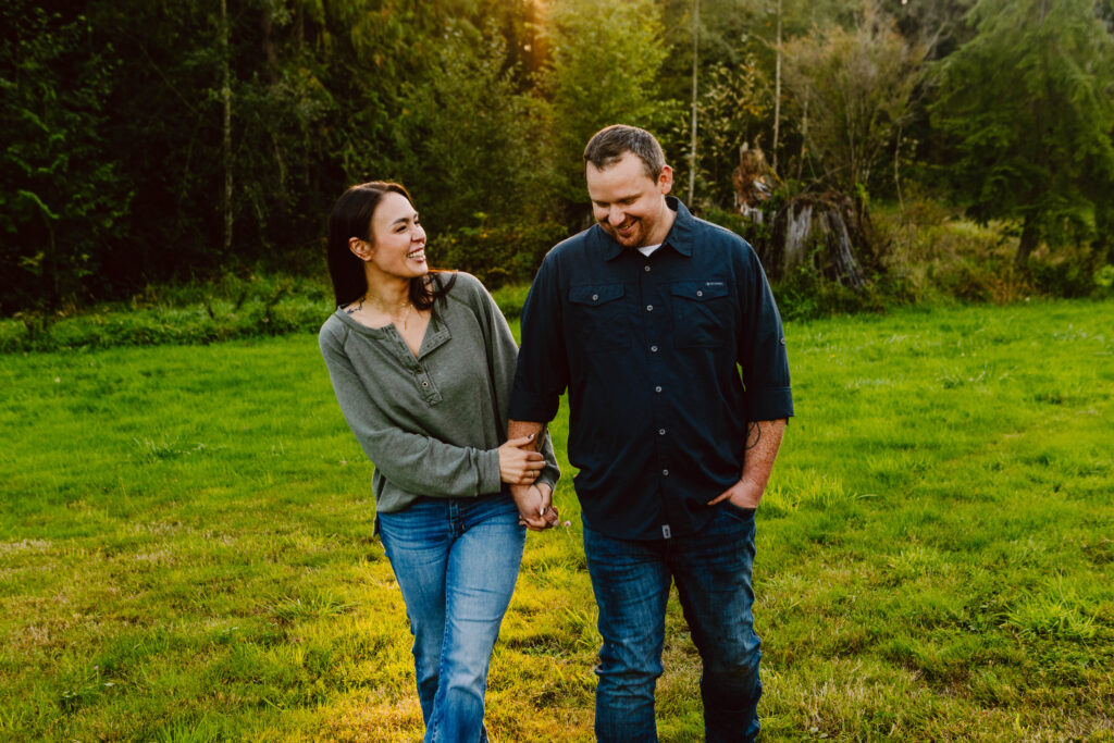 Snohomish Wedding Photographer GSquared Weddings A couple is walking hand in hand on a grassy field surrounded by trees their smiles captured in beautiful photos The sun shines through the foliage creating a warm glow Casually dressed in jeans and shirts they look lovingly at each other amid natures serene backdrop Serving Seattle Snohomish and Washington State Snohomish Wedding Photographer GSquared Weddings A couple is walking hand in hand on a grassy field surrounded by trees, their smiles captured in beautiful photos. The sun shines through the foliage, creating a warm glow. Casually dressed in jeans and shirts, they look lovingly at each other amid natures serene backdrop. Serving Seattle, Snohomish and Washington State