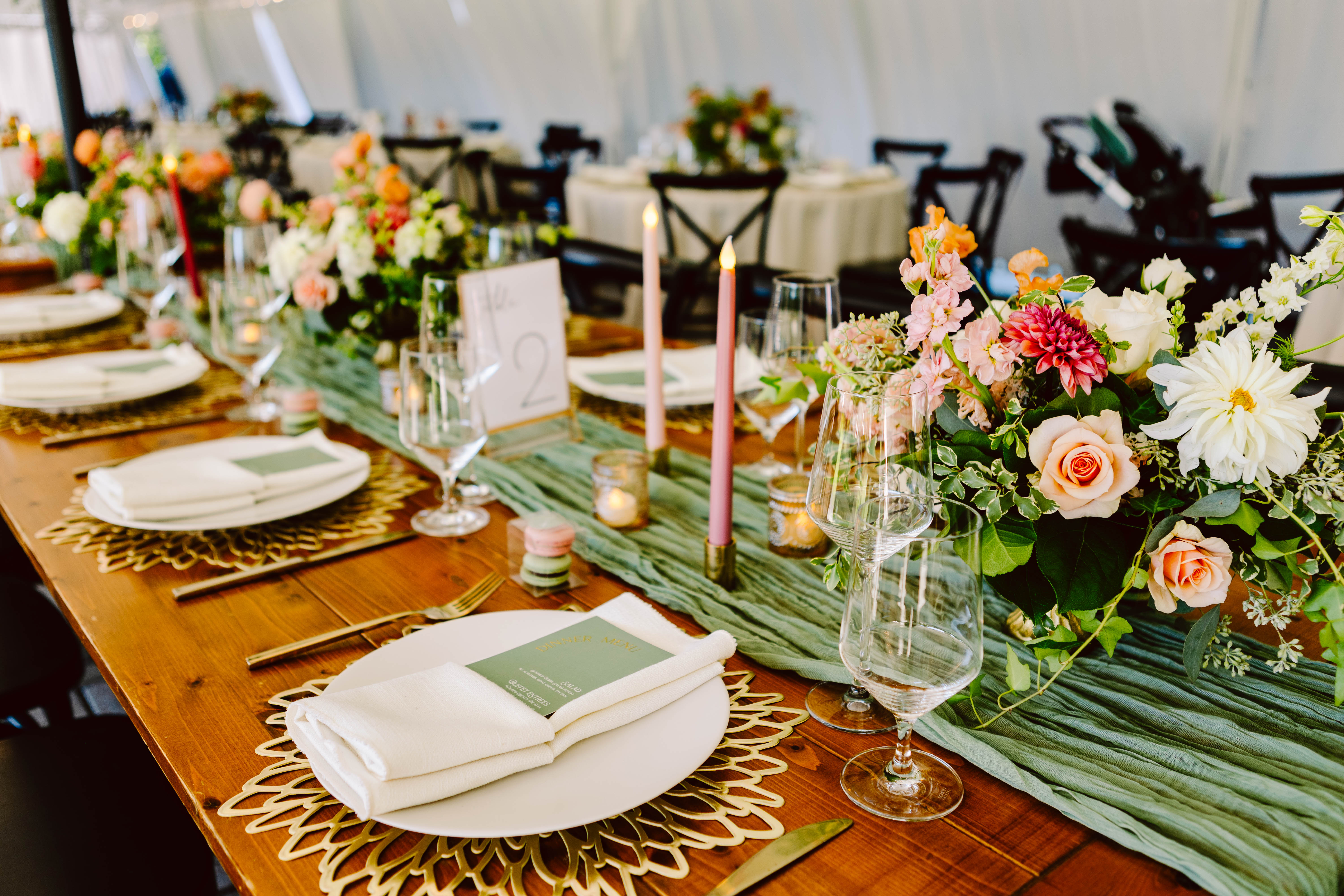 Snohomish Wedding Photographer GSquared Weddings A beautifully set wedding table blends elegance with budgetfriendly charm featuring white plates gold cutlery and neatly folded napkins A centerpiece of pink orange and white flowers paired with green fabric runners adorns the wooden table perfectly Serving Seattle Snohomish and Washington State