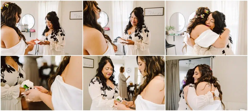 Snohomish Wedding Photographer GSquared Weddings In a sunlit room in Machias, a bride adorned with a floral crown and an off-shoulder dress shares a heartfelt moment with another woman. They exchange gifts, smile warmly, and embrace as their reflections dance in the mirror beside the soft curtains. Serving Seattle, Snohomish and Washington State