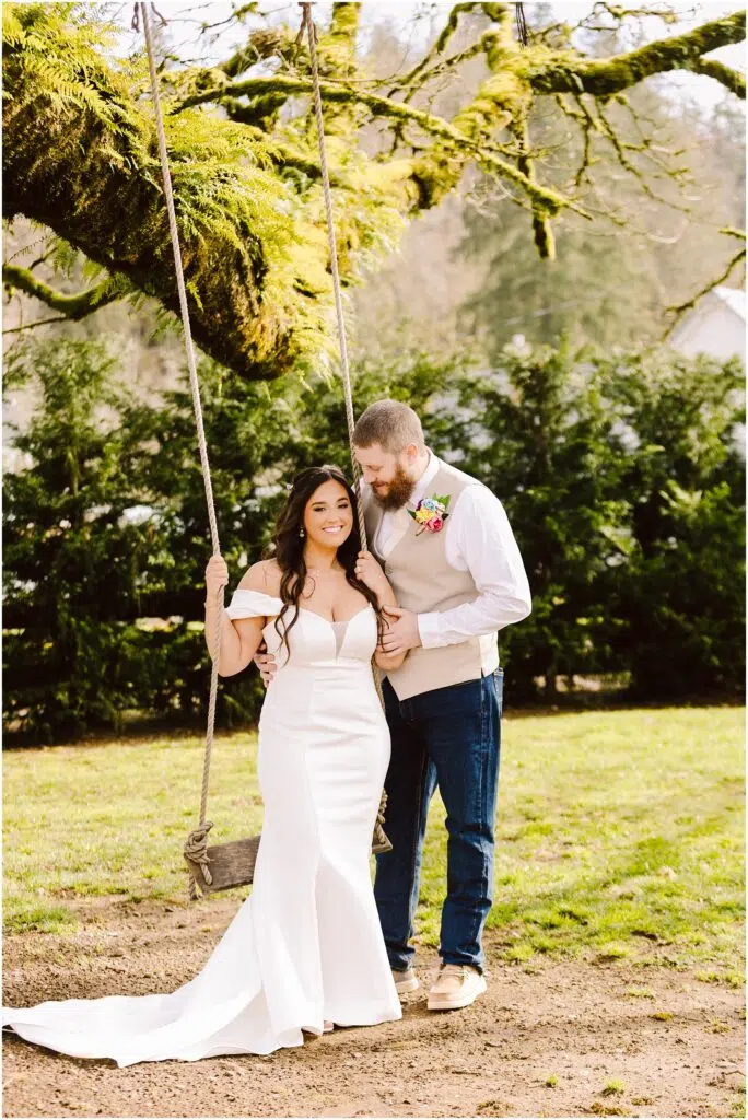 Snohomish Wedding Photographer GSquared Weddings A bride in a white wedding dress stands beside a groom in a shirt and vest with a boutonniere Theyre outdoors where the bride clings to a rope swing The backdrop of greenery hints at the serene beauty one might find in Machias Serving Seattle Snohomish and Washington State Snohomish Wedding Photographer GSquared Weddings A bride in a white wedding dress stands beside a groom in a shirt and vest with a boutonniere. Theyre outdoors, where the bride clings to a rope swing. The backdrop of greenery hints at the serene beauty one might find in Machias. Serving Seattle, Snohomish and Washington State