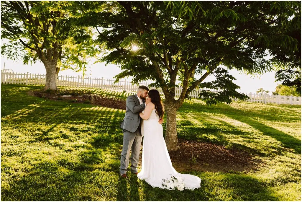 Snohomish Wedding Photographer GSquared Weddings A couple stands under a large tree in a sunlit Port Gamble garden The woman wears a white wedding dress and the man is in a gray suit Embracing lovingly theyre enveloped by sunlight filtering through the leaves embodying the essence of a perfect summer wedding day Serving Seattle Snohomish and Washington State Snohomish Wedding Photographer GSquared Weddings A couple stands under a large tree in a sunlit Port Gamble garden. The woman wears a white wedding dress, and the man is in a gray suit. Embracing lovingly, theyre enveloped by sunlight filtering through the leaves, embodying the essence of a perfect summer wedding day. Serving Seattle, Snohomish and Washington State