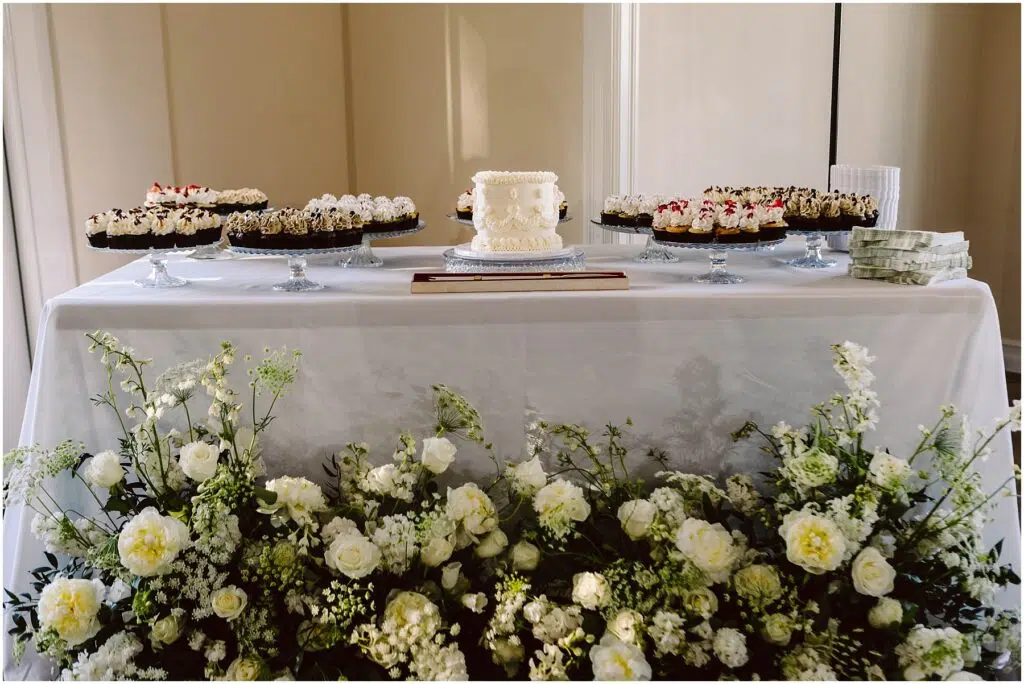 Snohomish Wedding Photographer GSquared Weddings At a charming Port Gamble summer wedding a dessert table features a small white cake at its center surrounded by an array of cupcakes displayed on glass stands The setup is enhanced with a pristine white cloth and an elegant arrangement of white flowers gracing the front Serving Seattle Snohomish and Washington State Snohomish Wedding Photographer GSquared Weddings At a charming Port Gamble summer wedding, a dessert table features a small white cake at its center, surrounded by an array of cupcakes displayed on glass stands. The setup is enhanced with a pristine white cloth and an elegant arrangement of white flowers gracing the front. Serving Seattle, Snohomish and Washington State