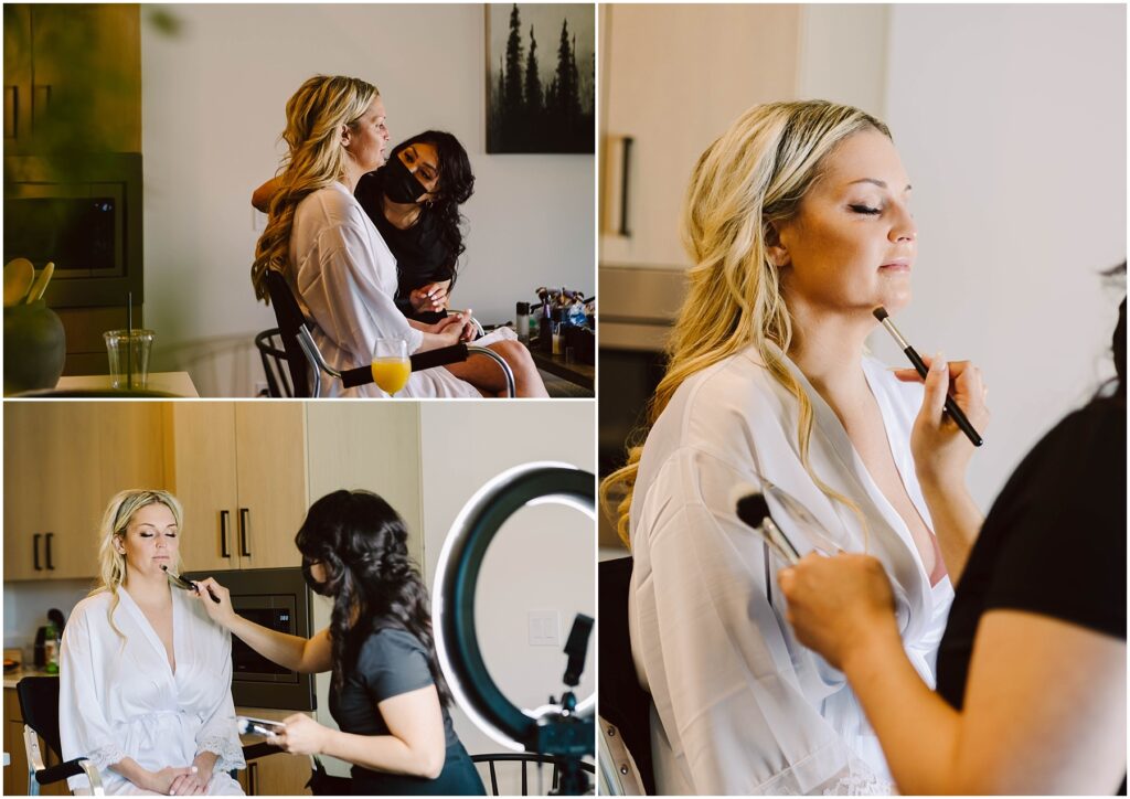 Snohomish Wedding Photographer GSquared Weddings A woman with long blonde hair in a white robe is having her makeup done by a stylist, reminiscent of the meticulous care taken at a winery. The stylist expertly applies makeup with brushes, framed by the glow of a ring light and an array of makeup products. Serving Seattle, Snohomish and Washington State