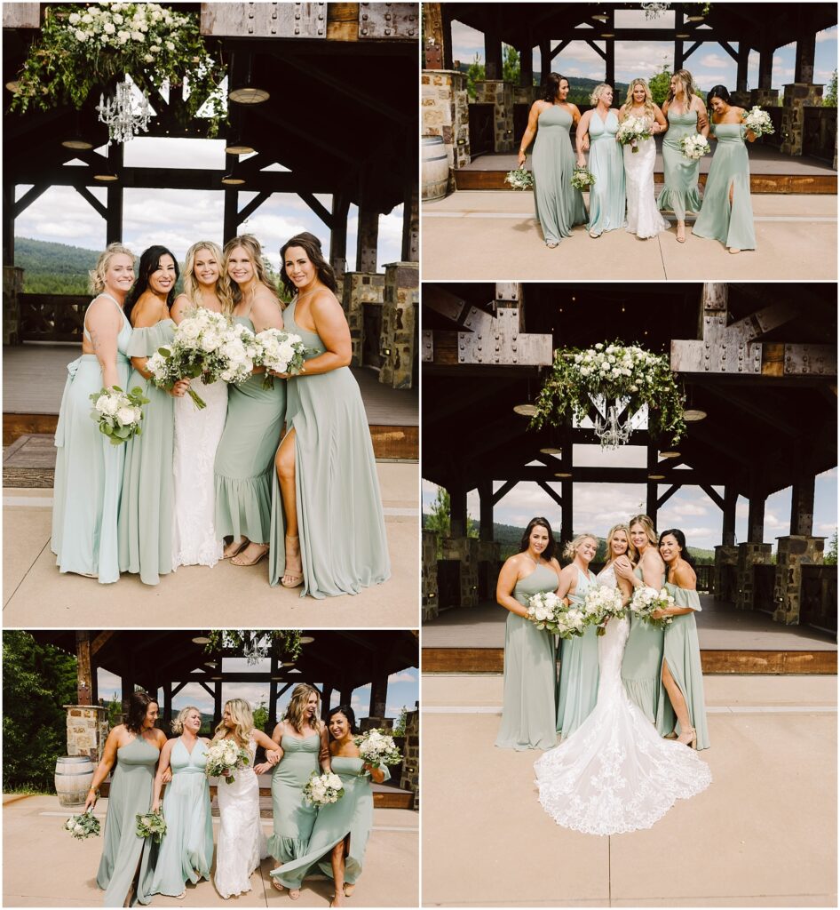 Snohomish Wedding Photographer GSquared Weddings A bride in a white gown poses with five bridesmaids in sage green dresses at a rustic winery pavilion, surrounded by lush greenery. Wooden beams and floral decorations hanging above complete the enchanting outdoor setting. Serving Seattle, Snohomish and Washington State