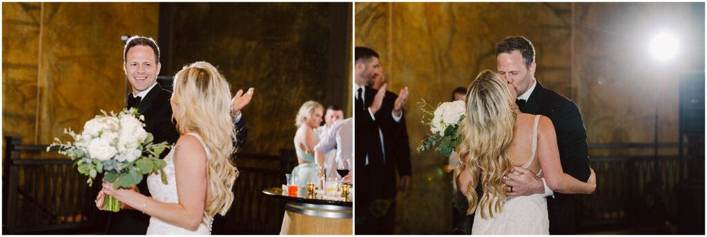 Snohomish Wedding Photographer GSquared Weddings A couple in formal attire shares a joyful moment at a winery celebration. The man, wearing a tuxedo, smiles broadly with open arms, while the woman, in a white dress holding a bouquet, looks at him. They are surrounded by applauding guests amid the rustic charm of the vineyard. Serving Seattle, Snohomish and Washington State