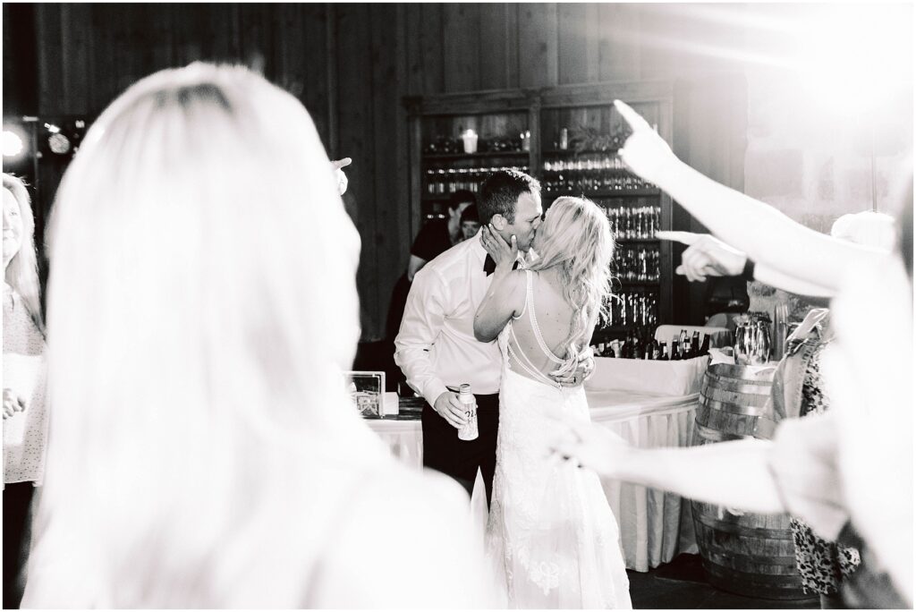 Snohomish wedding photographer gsquared weddings a couple shares a kiss on the dance floor at a wedding reception in a rustic winery The groom holds a drink while guests around them celebrate with raised hands The brides dress features a detailed back design adding elegance to the festive atmosphere Serving seattle snohomish and washington state Snohomish wedding photographer gsquared weddings a couple shares a kiss on the dance floor at a wedding reception in a rustic winery The groom holds a drink while guests around them celebrate with raised hands The brides dress features a detailed back design adding elegance to the festive atmosphere Serving seattle snohomish and washington state