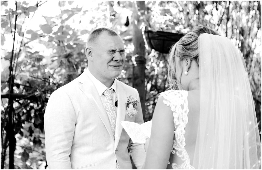 Snohomish Wedding Photographer GSquared Weddings Amidst the lush greenery of Snohomish a bride and groom stand during their wedding ceremony The groom in a light suit appears emotional as the bride wearing a lacy dress and veil reads from a paper Capturing this moment in black and white adds to its timeless elegance Serving Seattle Snohomish and Washington State Snohomish Wedding Photographer GSquared Weddings Amidst the lush greenery of Snohomish, a bride and groom stand during their wedding ceremony. The groom, in a light suit, appears emotional as the bride, wearing a lacy dress and veil, reads from a paper. Capturing this moment in black and white adds to its timeless elegance. Serving Seattle, Snohomish and Washington State