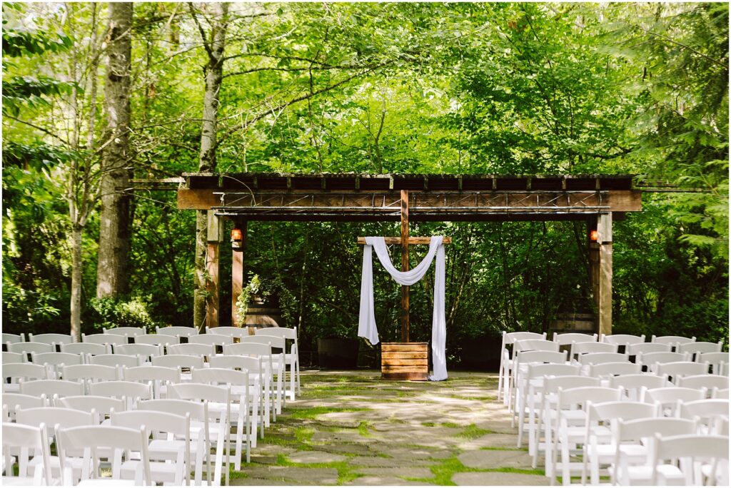 Snohomish Wedding Photographer GSquared Weddings An outdoor wedding setup in Snohomish features rows of white chairs facing a wooden arbor draped with white fabric The lush green trees and foliage create a serene forest setting under clear daylight perfect for a tranquil celebration Serving Seattle Snohomish and Washington State Snohomish Wedding Photographer GSquared Weddings An outdoor wedding setup in Snohomish features rows of white chairs facing a wooden arbor draped with white fabric. The lush green trees and foliage create a serene forest setting under clear daylight, perfect for a tranquil celebration. Serving Seattle, Snohomish and Washington State