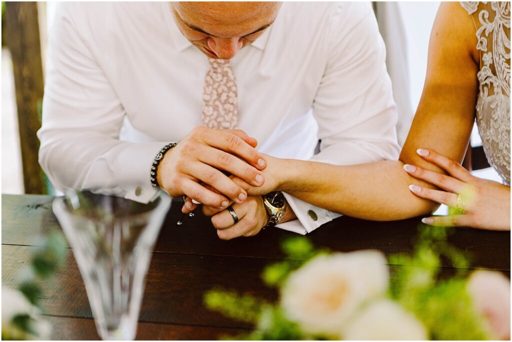 Snohomish Wedding Photographer GSquared Weddings In Snohomish a couple sits at a table the man gently holding the womans arm Hes dressed in a white shirt with a patterned tie and shes wearing a lace dress Their hands rest among the green floral arrangements on the table Serving Seattle Snohomish and Washington State Snohomish Wedding Photographer GSquared Weddings In Snohomish, a couple sits at a table, the man gently holding the womans arm. Hes dressed in a white shirt with a patterned tie, and shes wearing a lace dress. Their hands rest among the green floral arrangements on the table. Serving Seattle, Snohomish and Washington State