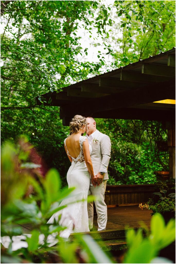 Snohomish Wedding Photographer GSquared Weddings In a lush green garden setting in Snohomish a bride and groom share a tender kiss The bride dazzles in her lacedetailed dress while the groom stands beside her in a lightcolored suit on a wooden platform embraced by vibrant foliage Serving Seattle Snohomish and Washington State Snohomish Wedding Photographer GSquared Weddings In a lush, green garden setting in Snohomish, a bride and groom share a tender kiss. The bride dazzles in her lace-detailed dress while the groom stands beside her in a light-colored suit on a wooden platform, embraced by vibrant foliage. Serving Seattle, Snohomish and Washington State