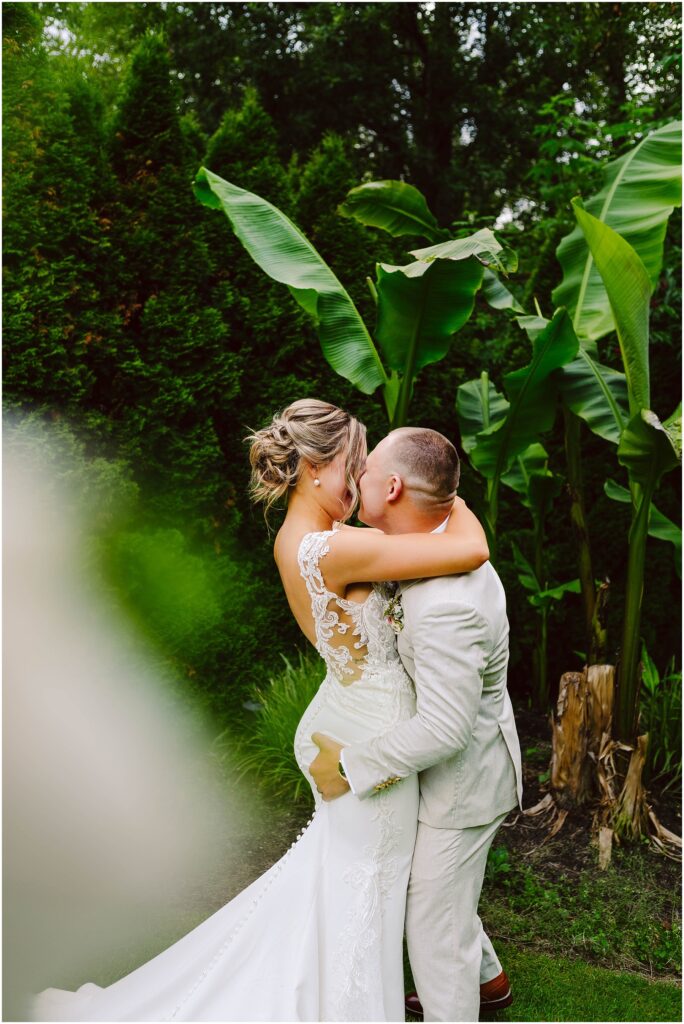 Snohomish Wedding Photographer GSquared Weddings A groom in a light suit joyfully lifts and kisses the bride adorned in a lace wedding dress They stand amidst lush greenery and large tropical leaves crafting a romantic atmosphere that feels straight out of Snohomishs enchanting landscapes Serving Seattle Snohomish and Washington State Snohomish Wedding Photographer GSquared Weddings A groom in a light suit joyfully lifts and kisses the bride, adorned in a lace wedding dress. They stand amidst lush greenery and large tropical leaves, crafting a romantic atmosphere that feels straight out of Snohomishs enchanting landscapes. Serving Seattle, Snohomish and Washington State