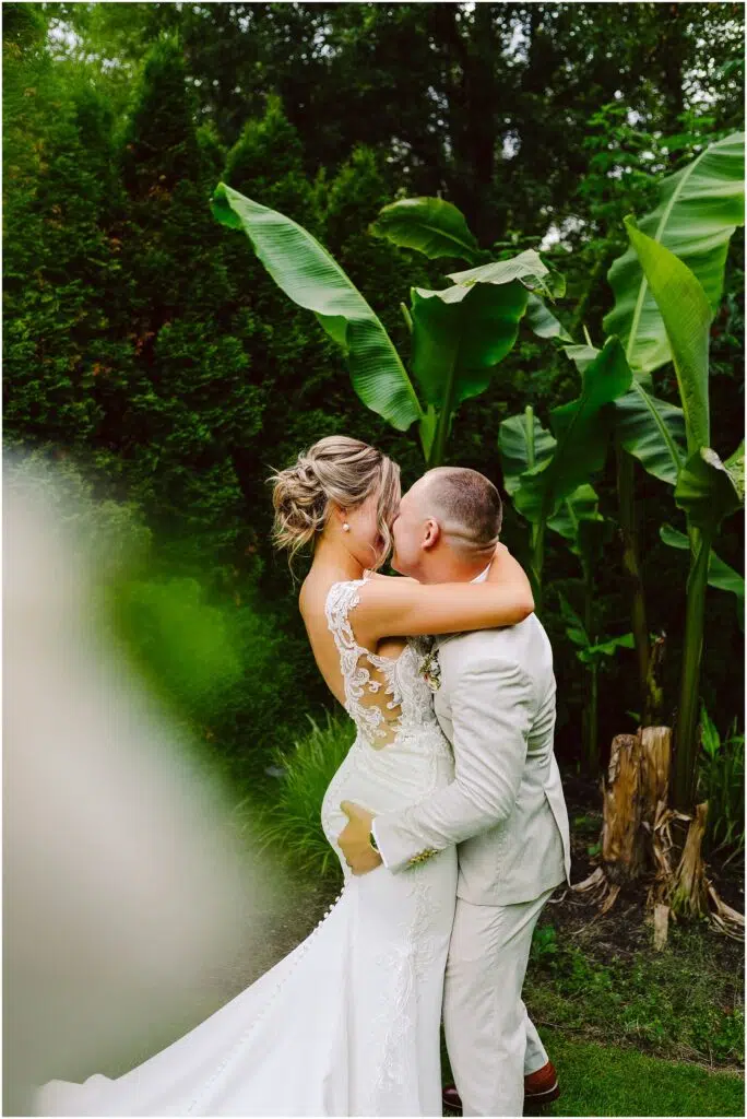 Snohomish Wedding Photographer GSquared Weddings A groom in a light suit joyfully lifts and kisses the bride adorned in a lace wedding dress They stand amidst lush greenery and large tropical leaves crafting a romantic atmosphere that feels straight out of Snohomishs enchanting landscapes Serving Seattle Snohomish and Washington State Snohomish Wedding Photographer GSquared Weddings A groom in a light suit joyfully lifts and kisses the bride, adorned in a lace wedding dress. They stand amidst lush greenery and large tropical leaves, crafting a romantic atmosphere that feels straight out of Snohomishs enchanting landscapes. Serving Seattle, Snohomish and Washington State