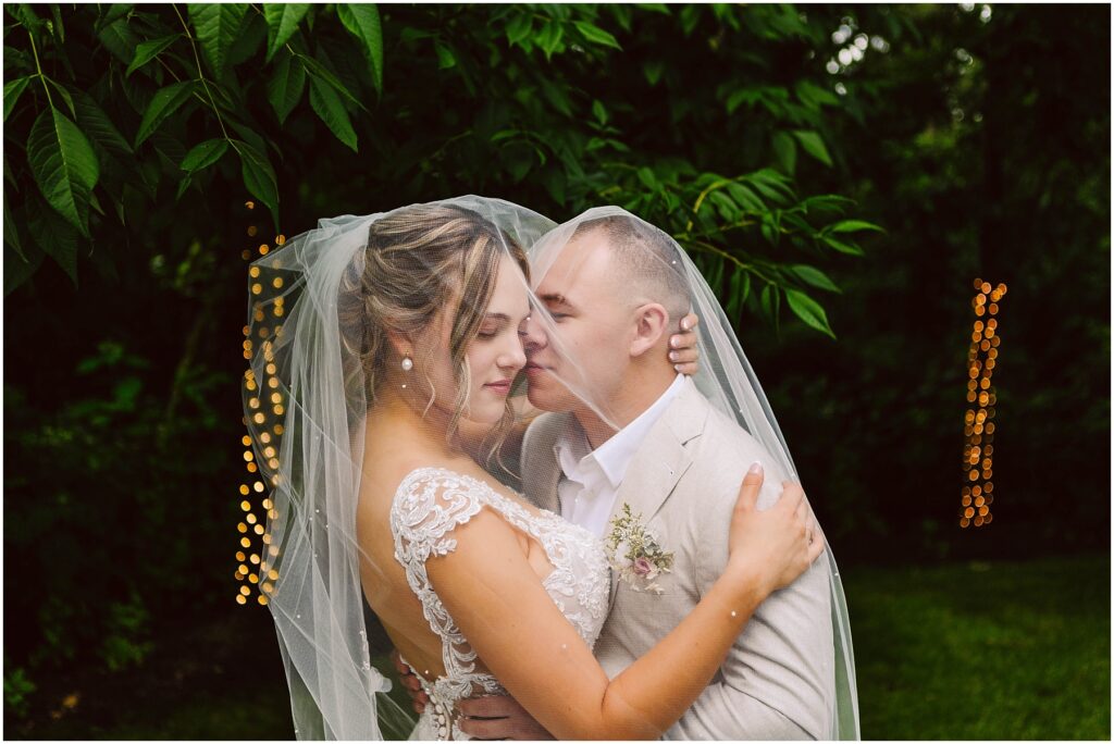 Snohomish Wedding Photographer GSquared Weddings In Snohomish a bride and groom embrace lovingly under a shared veil The bride wears a detailed lace wedding dress while the groom dons a lightcolored suit They are enveloped by lush green foliage with warm outoffocus lights twinkling in the background Serving Seattle Snohomish and Washington State Snohomish Wedding Photographer GSquared Weddings In Snohomish, a bride and groom embrace lovingly under a shared veil. The bride wears a detailed lace wedding dress while the groom dons a light-colored suit. They are enveloped by lush green foliage, with warm, out-of-focus lights twinkling in the background. Serving Seattle, Snohomish and Washington State