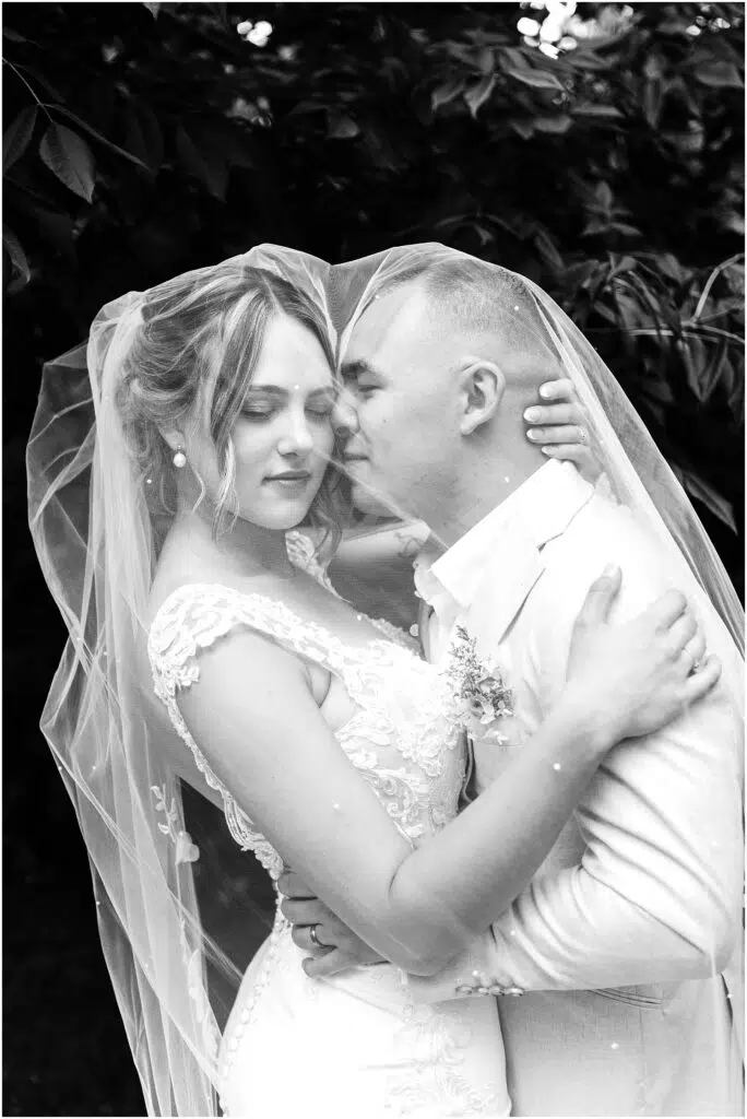 Snohomish Wedding Photographer GSquared Weddings Black and white photo of a couple embracing on their wedding day in Snohomish The bride is in a lace gown and veil while the groom sports a lightcolored suit Theyre surrounded by leafy trees creating a romantic intimate moment Serving Seattle Snohomish and Washington State Snohomish Wedding Photographer GSquared Weddings Black and white photo of a couple embracing on their wedding day in Snohomish. The bride is in a lace gown and veil, while the groom sports a light-colored suit. Theyre surrounded by leafy trees, creating a romantic, intimate moment. Serving Seattle, Snohomish and Washington State