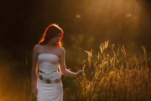 Woman in a white dress standing in a field of tall grass