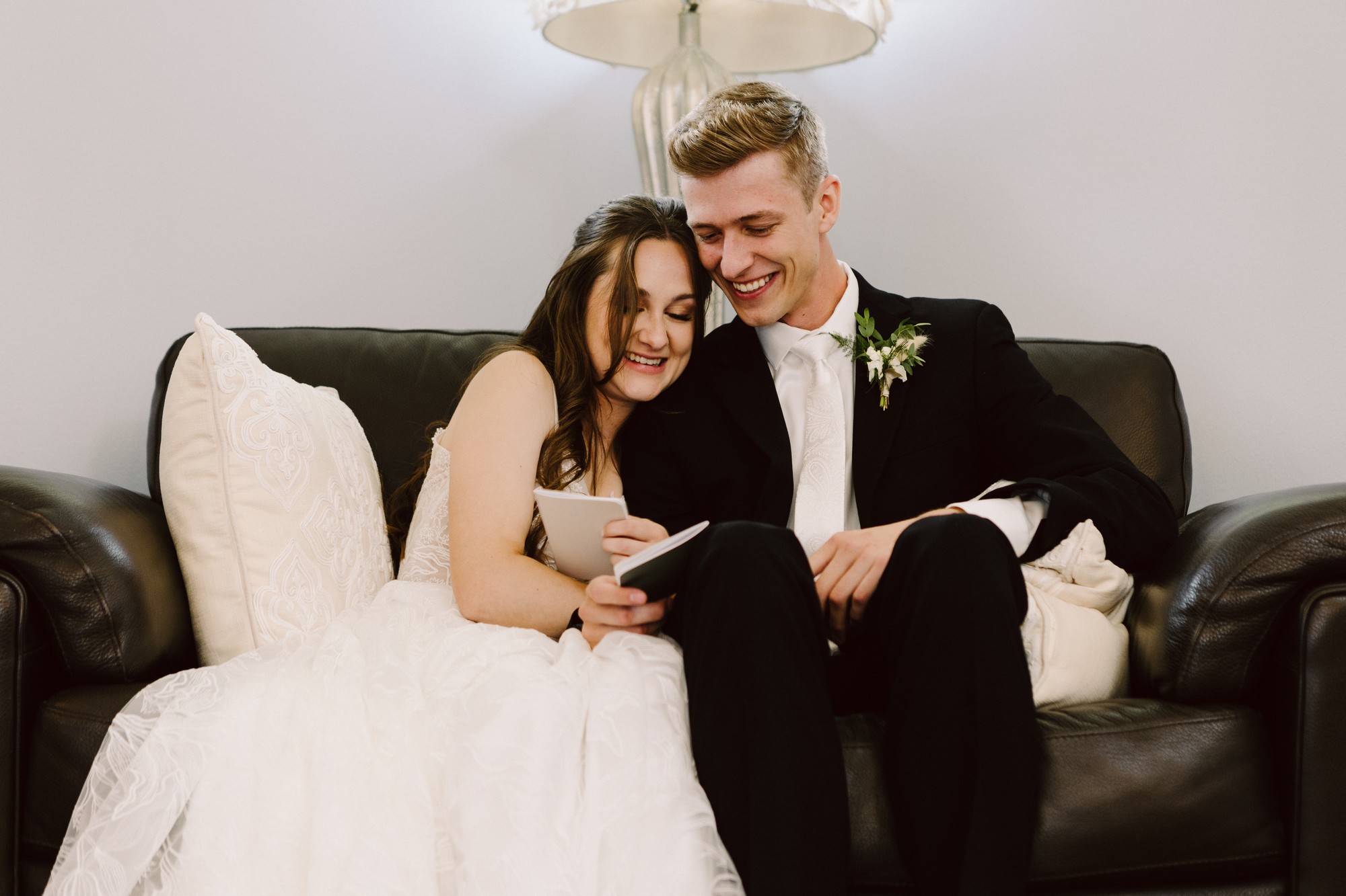 KGSW1205 bride and groom in a room on a couch snuggled together with their vow books taking a few private moments to read their vows to eachother before the ceremony