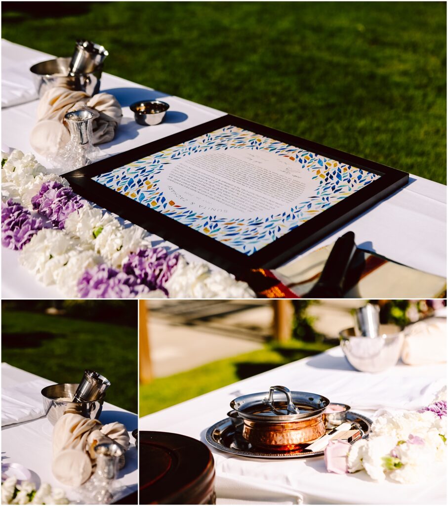 Outdoor table with a framed decorative document surrounded by flowers and ceremonial vessels copper pots on a white cloth