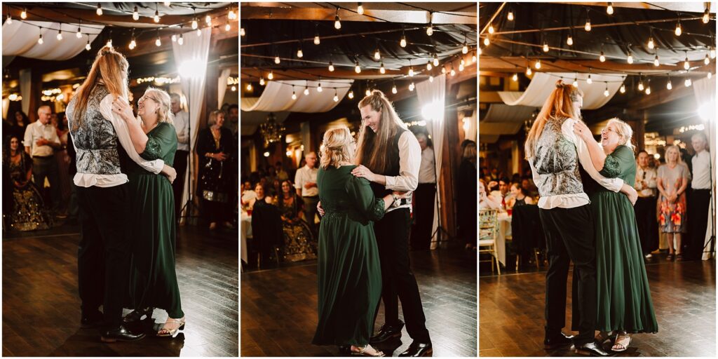 Couple dances closely under hanging bulbs as guests watch woman in green dress and man in patterned vest share a moment at a reception