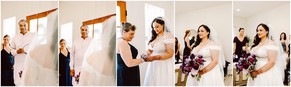 Bride in a white gown and veil stands with her parents and a bridesmaid in a sunlit room preparing for the ceremony