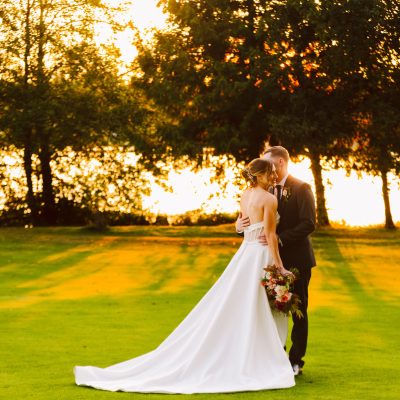 nile shrine golf course wedding bride and groom hugging in a orange and red glowing sunset by trees and a pond