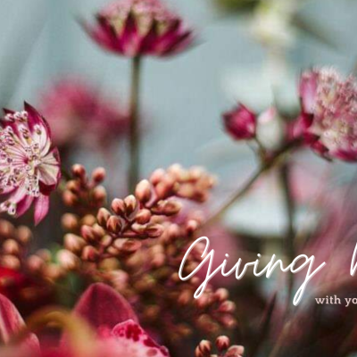 Snohomish Wedding Photographer GSquared Weddings A close-up of a floral arrangement featuring pink and red flowers and berries. The text Give Back with Your Wedding is elegantly scripted in white on the right side, adding a touch of grace to the heartfelt message. Serving Seattle, Snohomish and Orlando